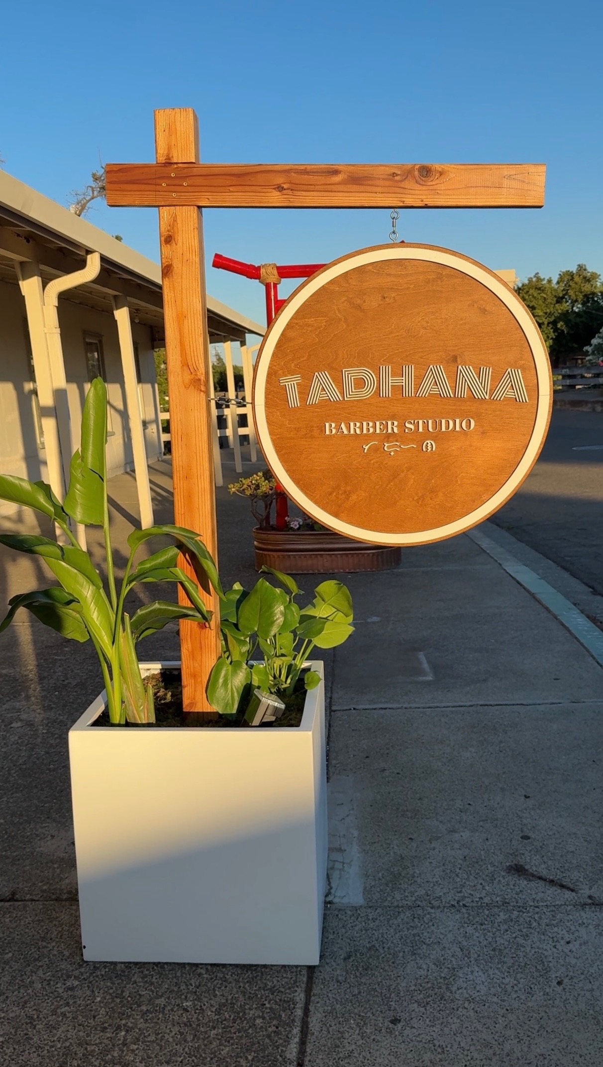 The round wooden Tadhana Barber Studio sign outside the entrance